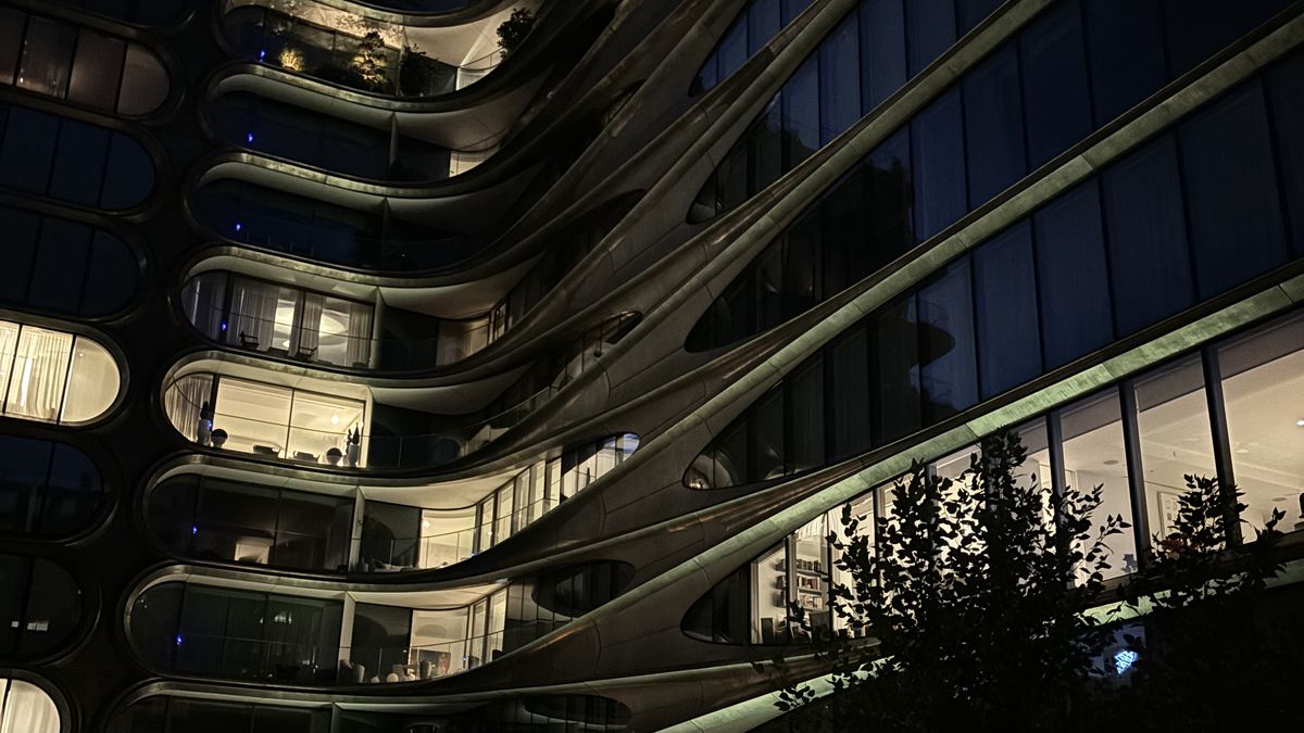 A curving residential building lit at night