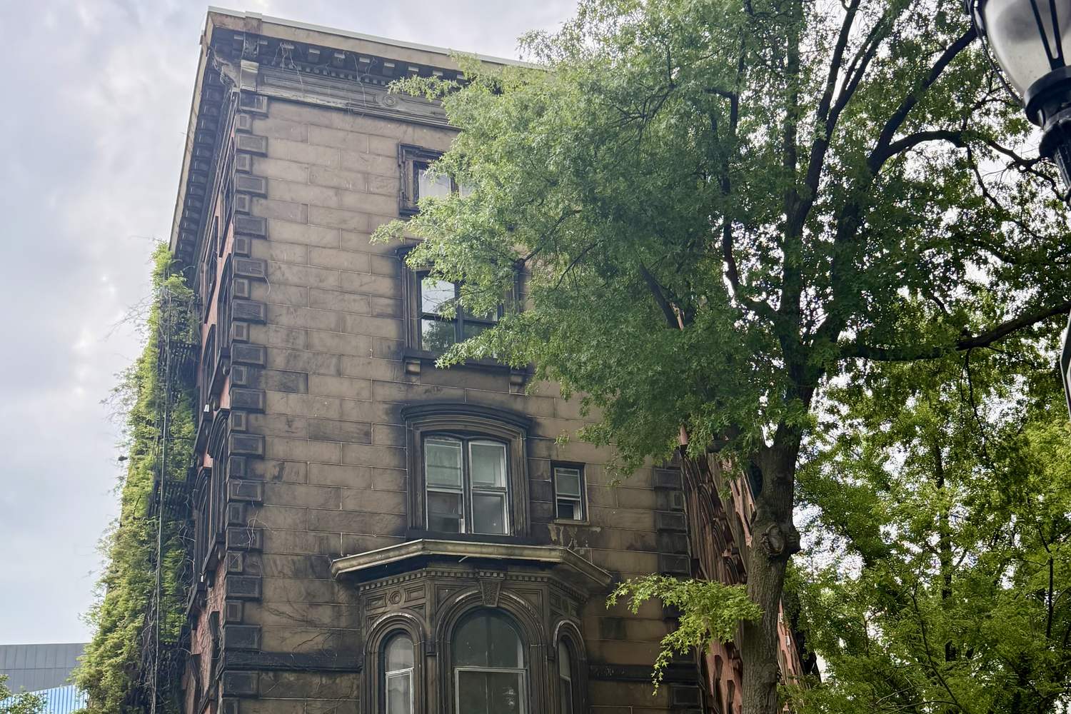 Brownstone corner building framed by trees in the East Village